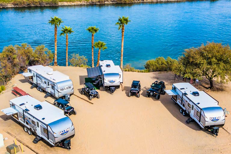 Spacious RV parking spots under a clear blue sky at Pirate Cove Resort, surrounded by palm trees.