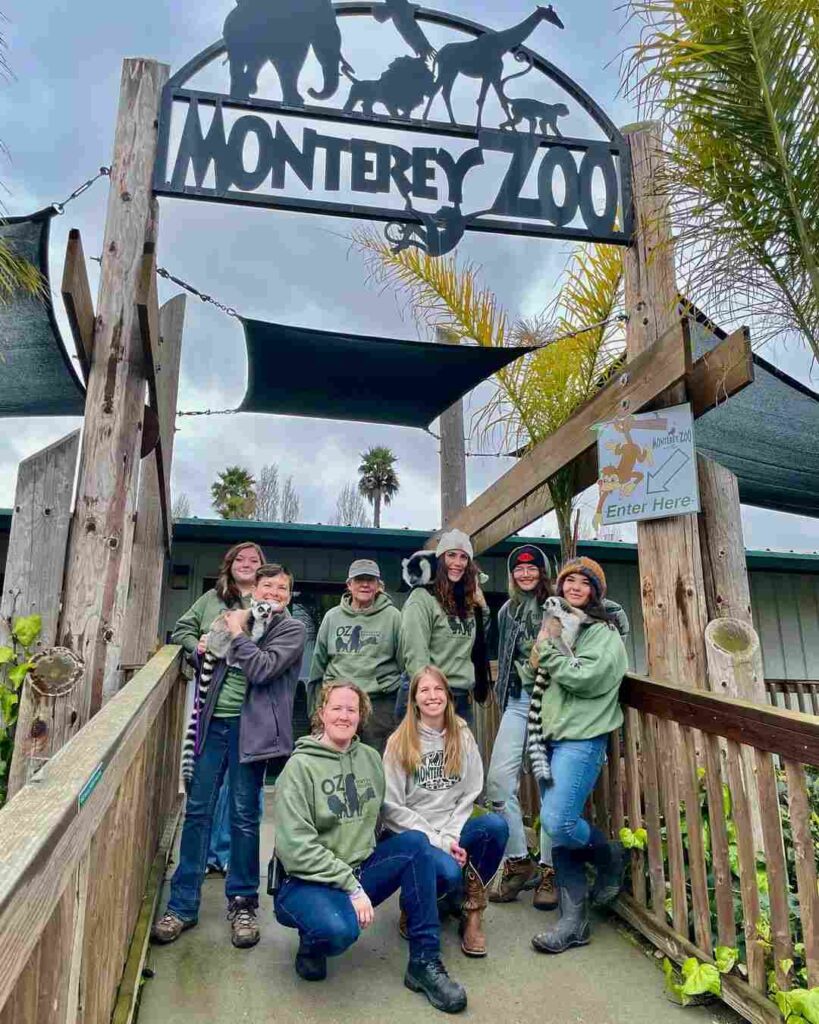 Family smiling at Monterey Zoo entrance beneath the welcome sign.