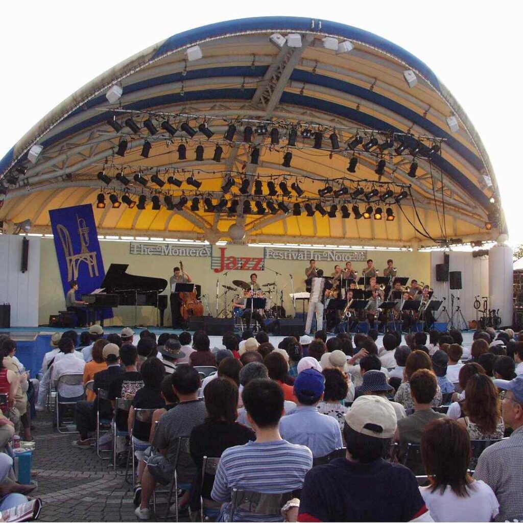 Audience seated under a grand marquee at a live music event