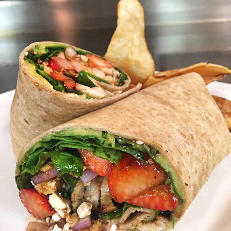 A fresh and healthy grilled chicken wrap served with a side salad at Crazy Horse Restaurant, highlighting the menu's diverse options