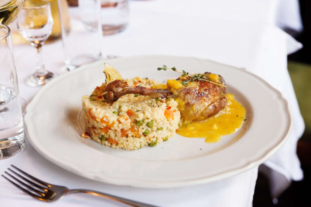 Chicken drumstick in savory gravy served with vegetable risotto in restaurant