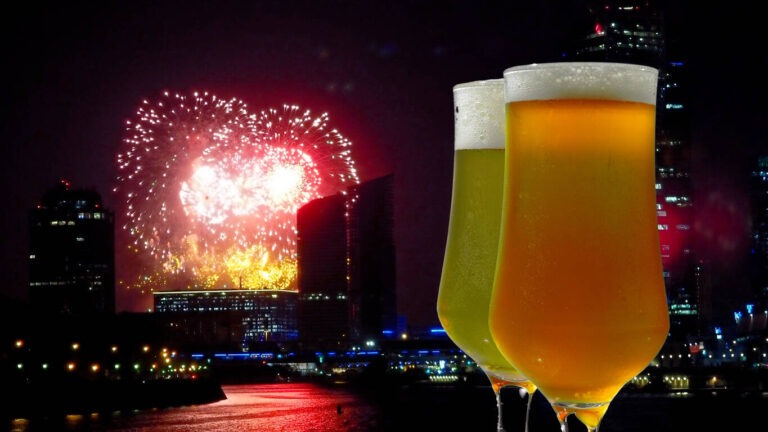 Two glasses of cold beer. Close-up view from the sidewalk cafe over night city with fireworks display