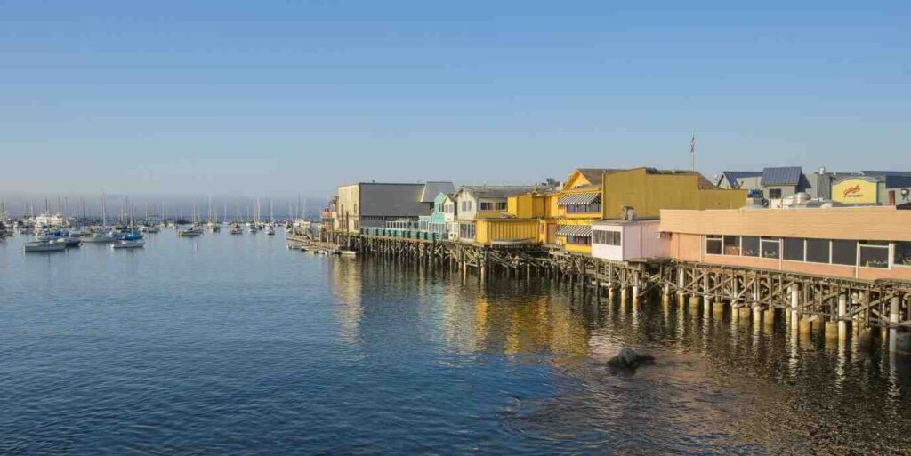 Scenic view of Monterey Wharf with boats docked on calm blue waters under clear skies.