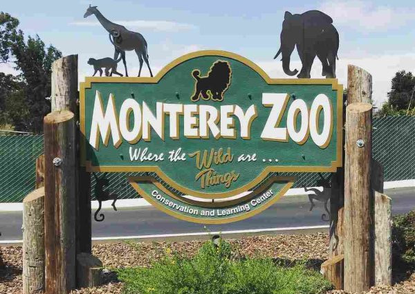 Entrance sign of the Monterey Zoo with lush foliage in the background
