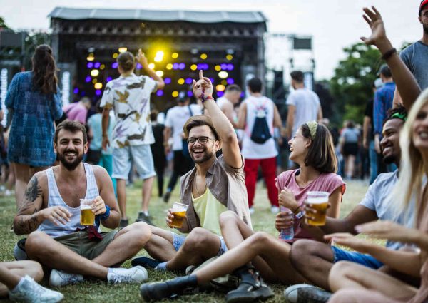 Group of friends having fun on grass during music festival.
